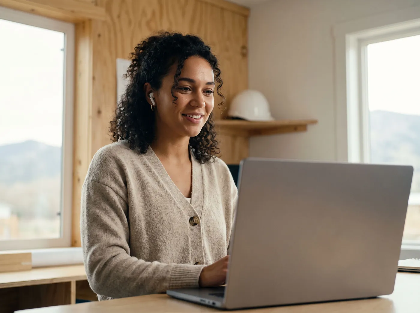 An office manager smiling at her laptop with one earbud in, mid-way through a training session